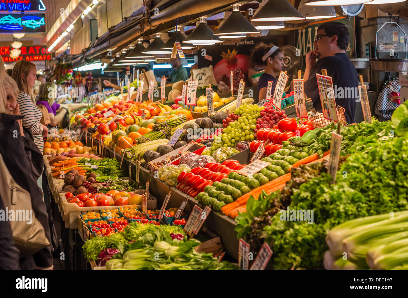 Shoppers with a display of fruits and vegetables with signs at a produce market stall Pike Place Market Seattle, Washington, USA Stock Photo