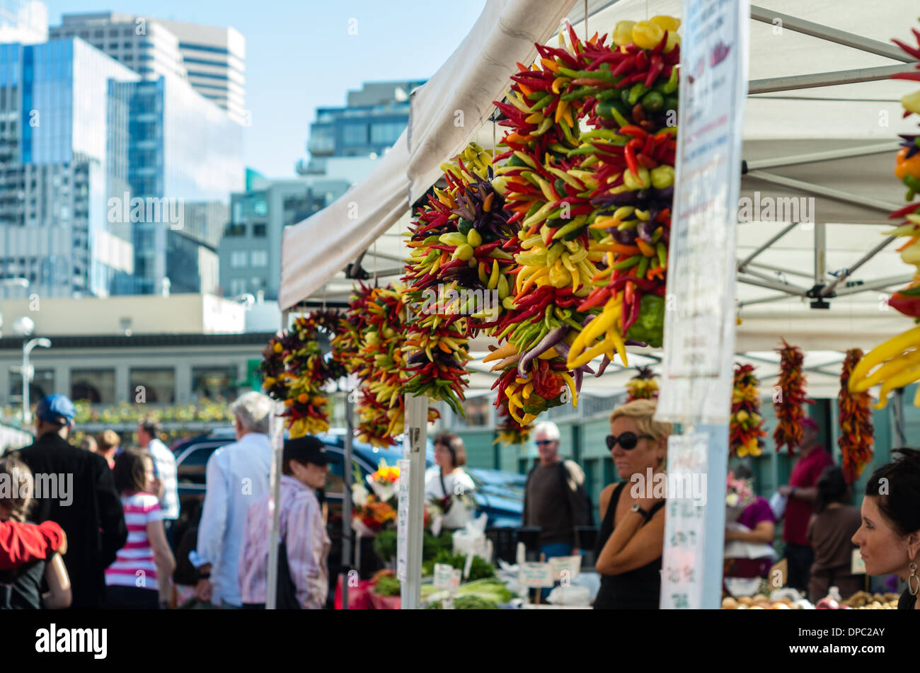 Shoppers with hot peppers strung on rope to dry at an open air market stall.  Pike Place Market, Seattle, Washington Stock Photo