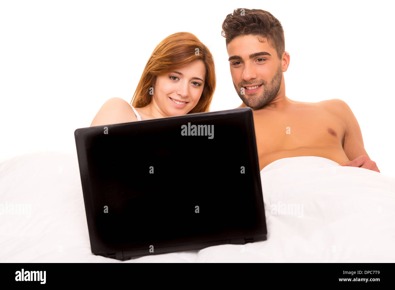 Happy couple watching a movie in bed Stock Photo - Alamy