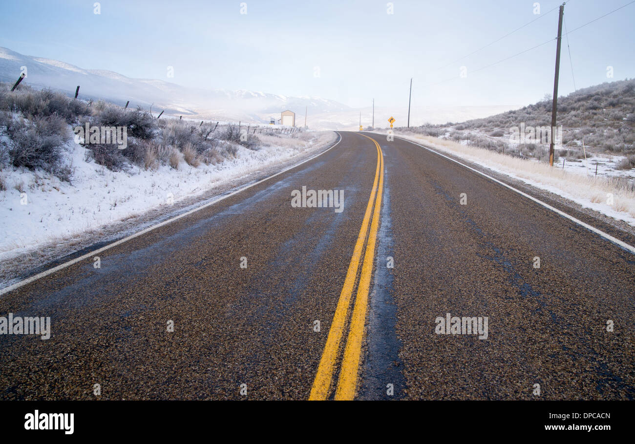 An icy road leads through country scene farm ranch hillside highway 71 Stock Photo