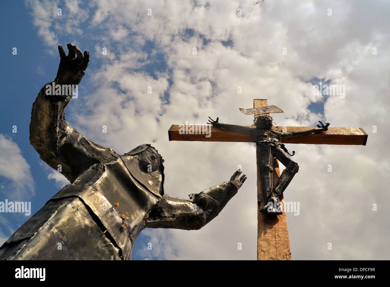 Modern steel statue of Christ with Virgin Mary lying at his feet against blue sky Stock Photo
