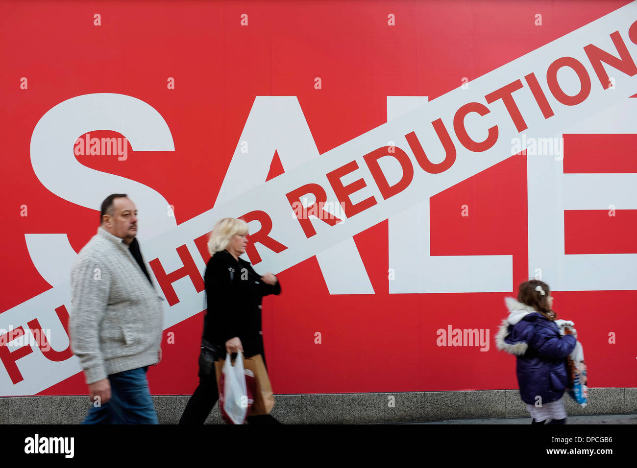 People walking past the Sale sign outside a shop Stock Photo