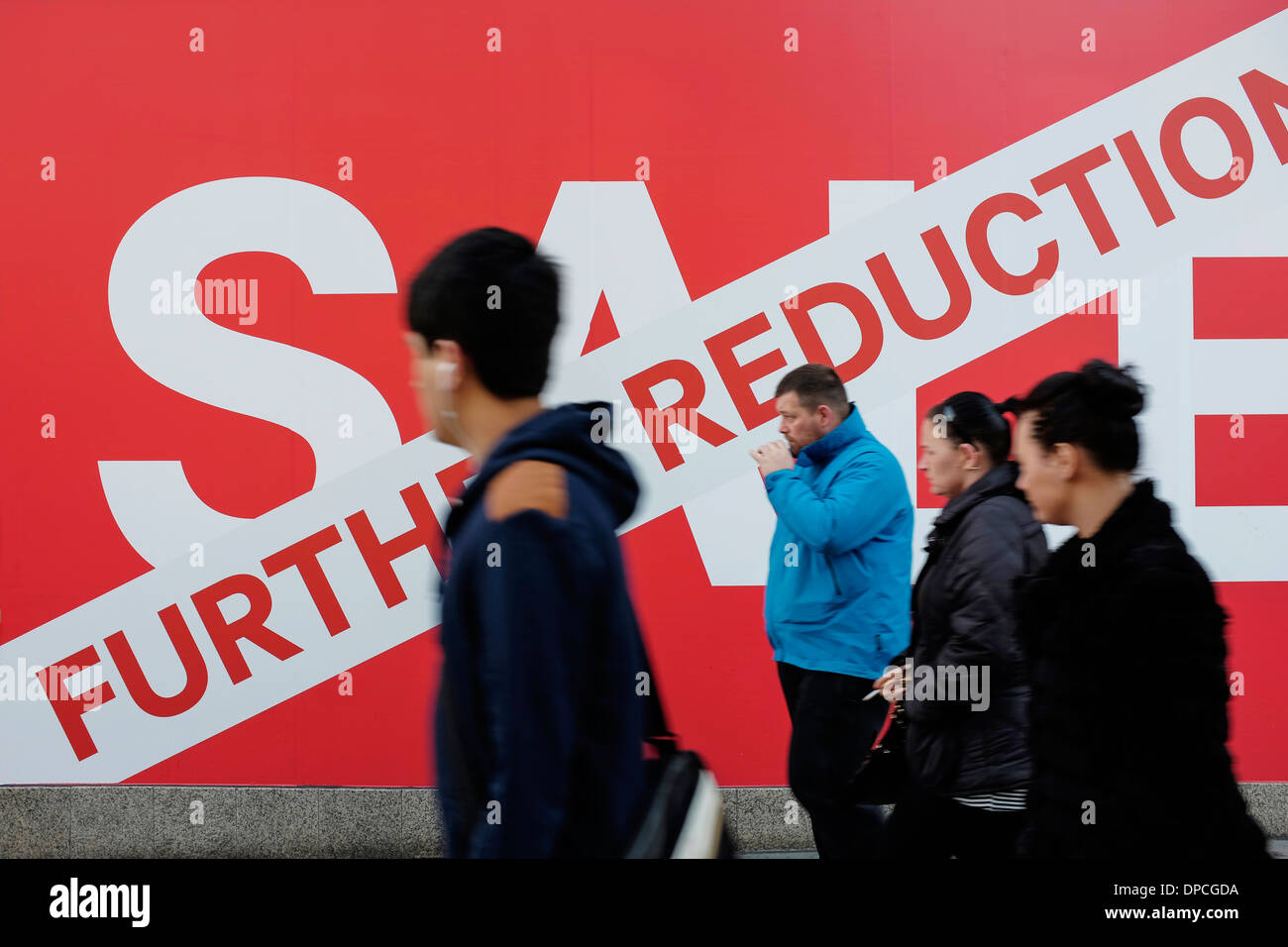 People walking past the Sale sign outside a shop Stock Photo