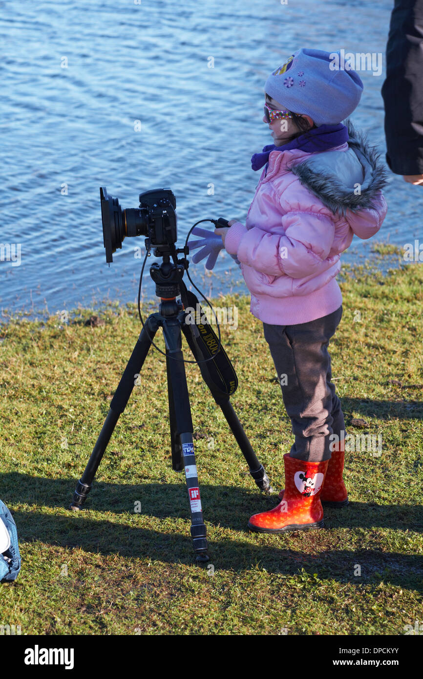 young photographer - young girl holding remote control to take a photo with Nikon D800 camera and Acratech tripod Stock Photo