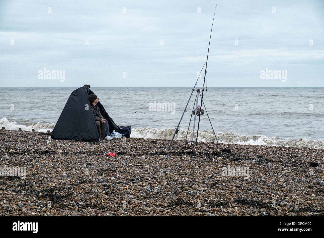 A sea fisherman sits in a shelter watching his fishing rod on a West Sussex beach. Picture by Julie Edwards Stock Photo