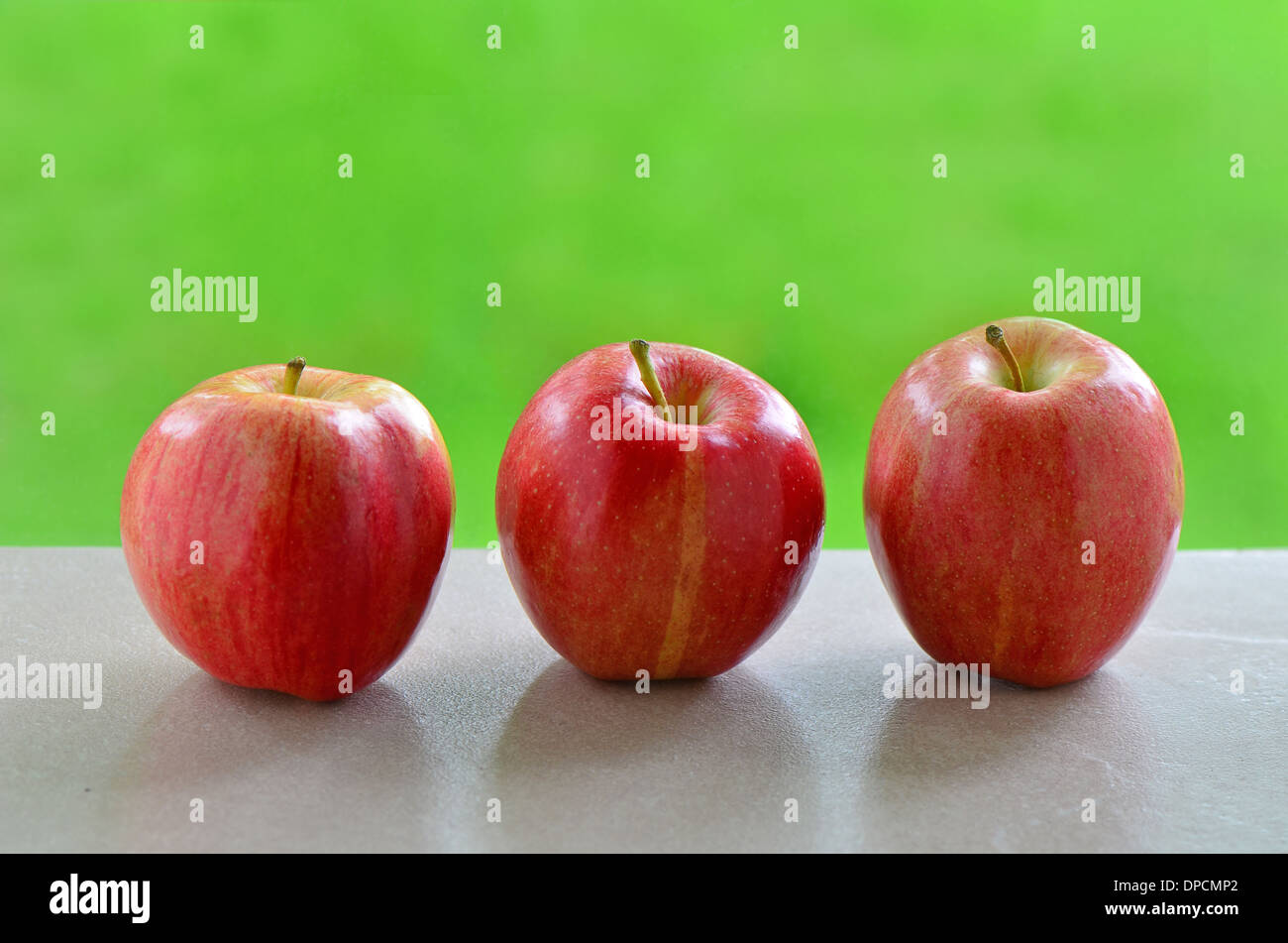 Delicious Gala apples on windowsill with vibrant green background Stock Photo