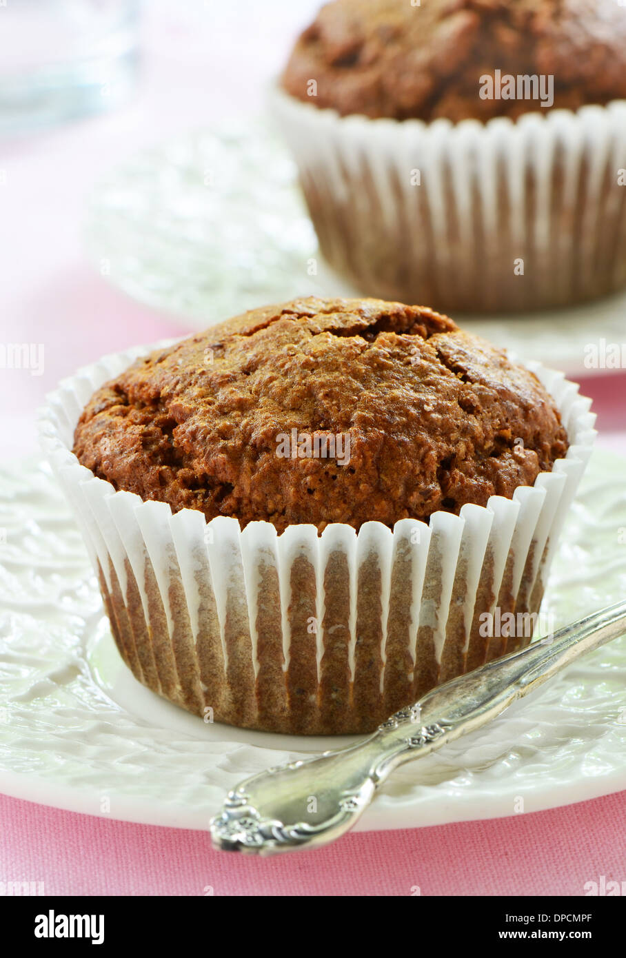 Bran muffins on cream colored rippled plates in vertical format Stock Photo