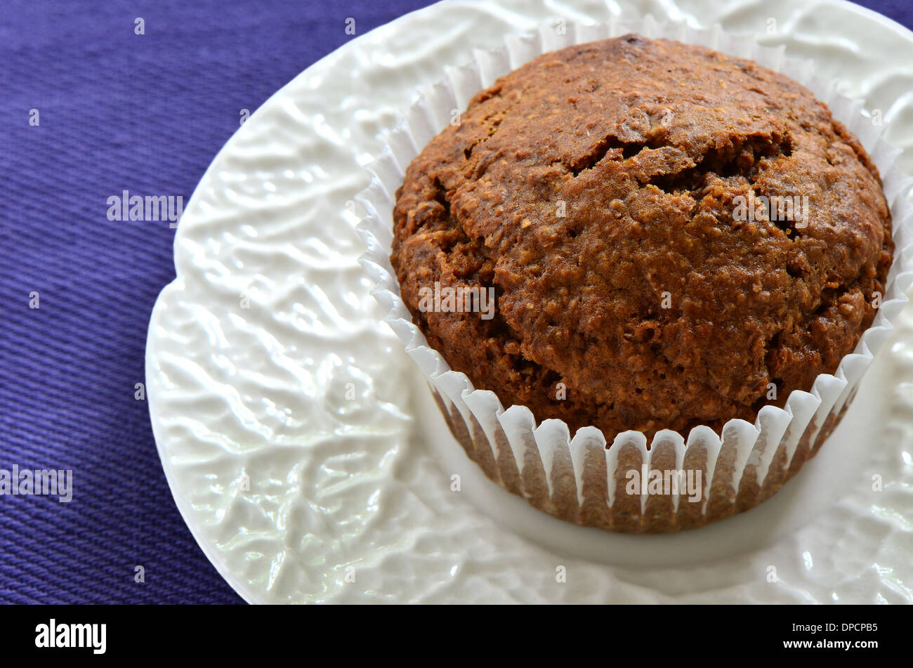 Bran muffin on white rippled plate Stock Photo
