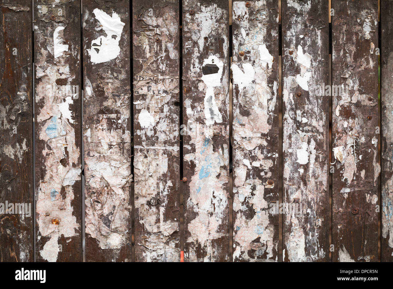 Old wooden fence background texture with scraps of paper ads Stock Photo