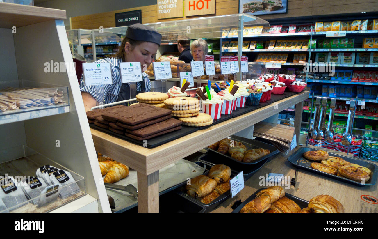 A Waitrose supermarket worker serving at cupcake, cookie and pastry