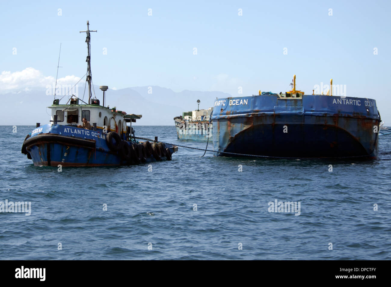 A tugboat towing two huge barges off the coast of Batangas, Philippines. Stock Photo