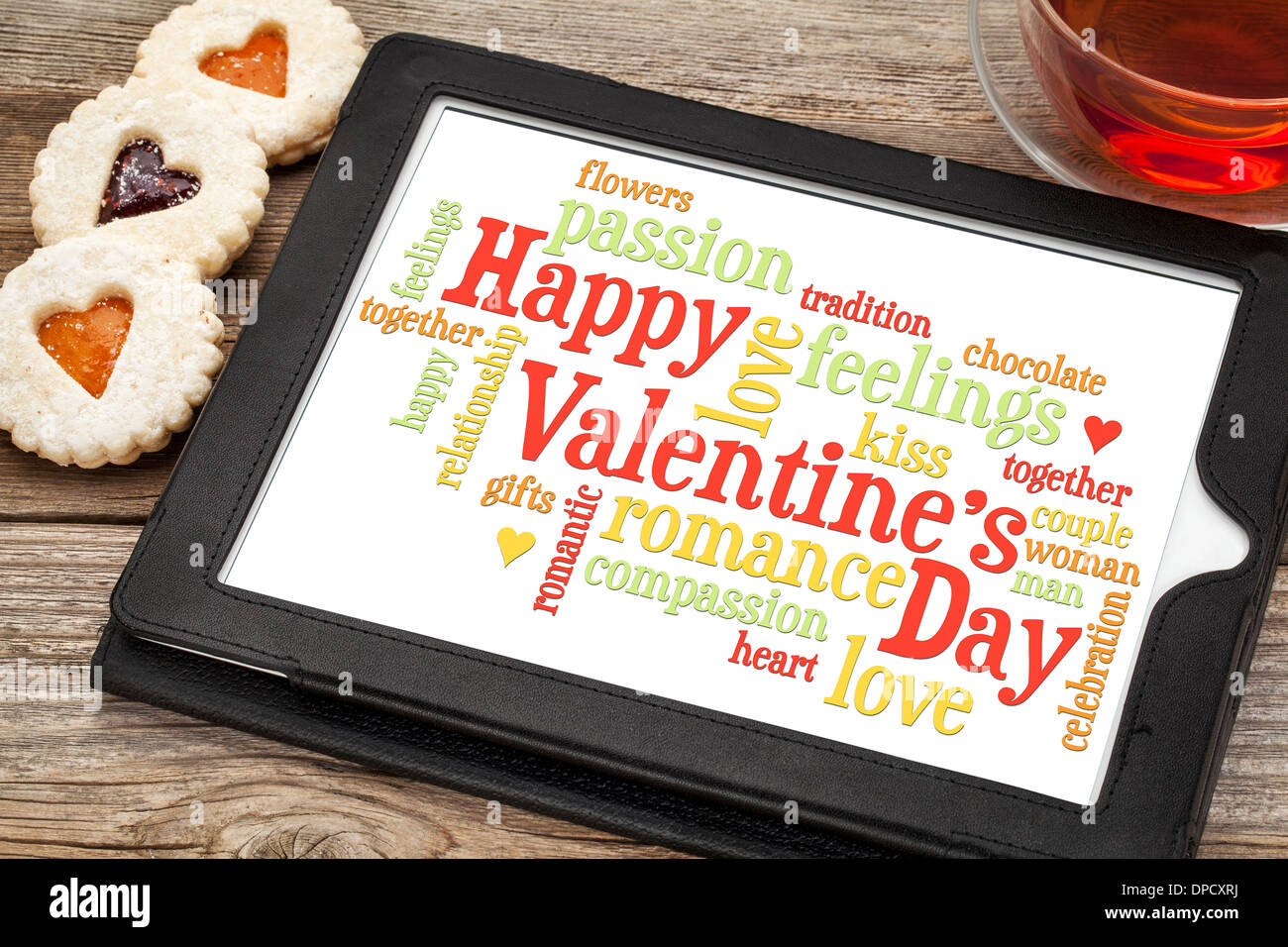 Happy Valentines Day word cloud on a digital tablet with heart cookies and a cup of tea Stock Photo