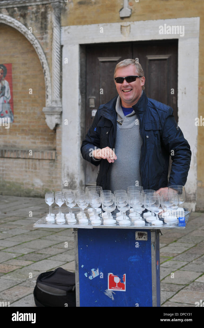 A man playing glass harp harmonica, that looks like crystal wine glass