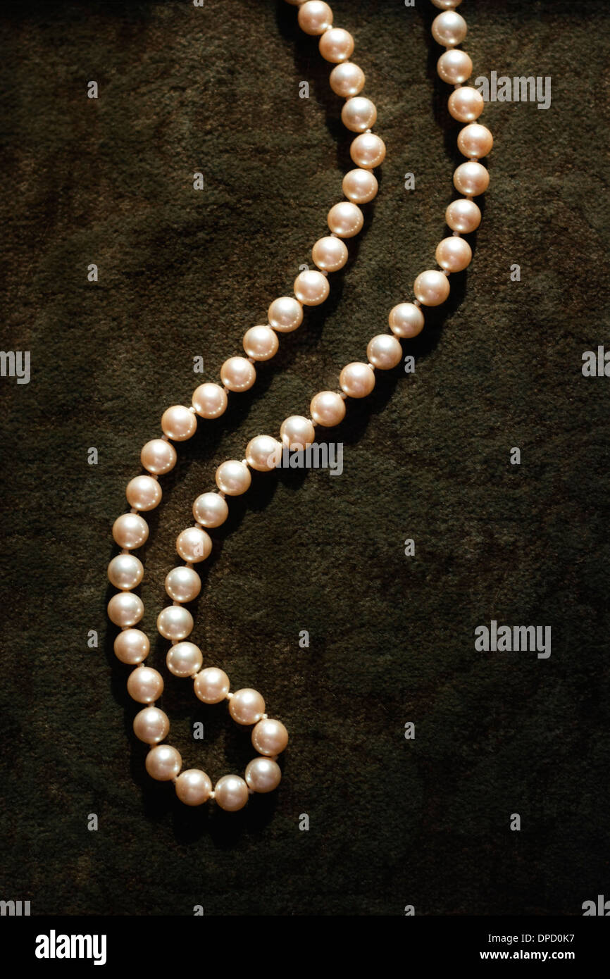 A single strand of pearls on a velvety brocade Stock Photo Alamy