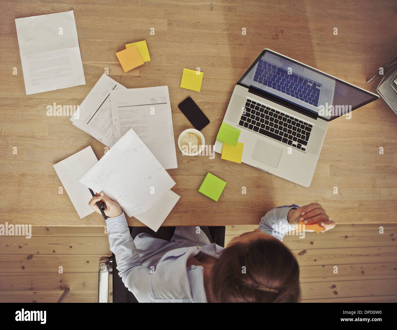 Top view of young woman working at her desk with laptop and documents. Business woman working at desk in office. Stock Photo