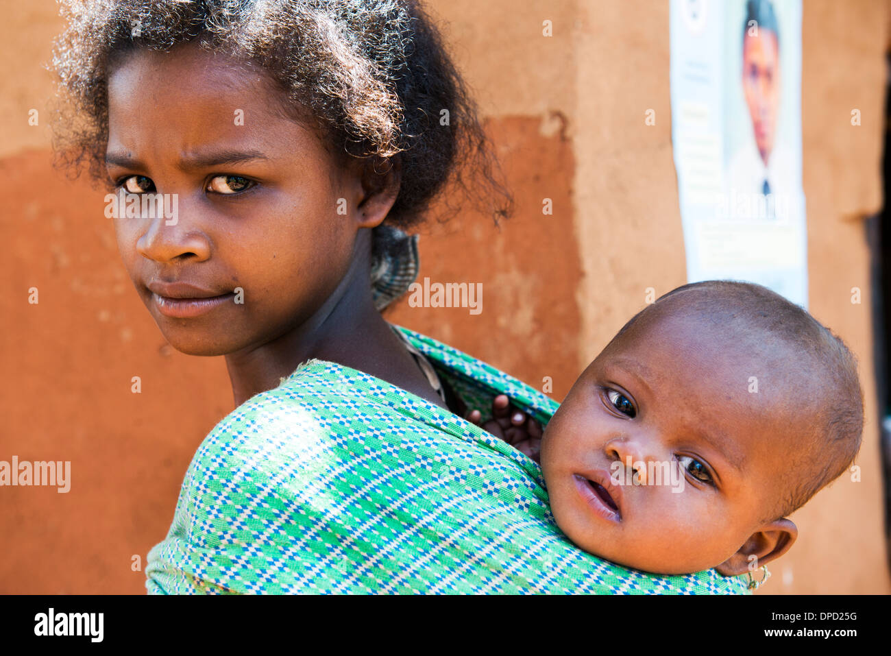 Siblings. A young girl carrying her infant sibling. Stock Photo