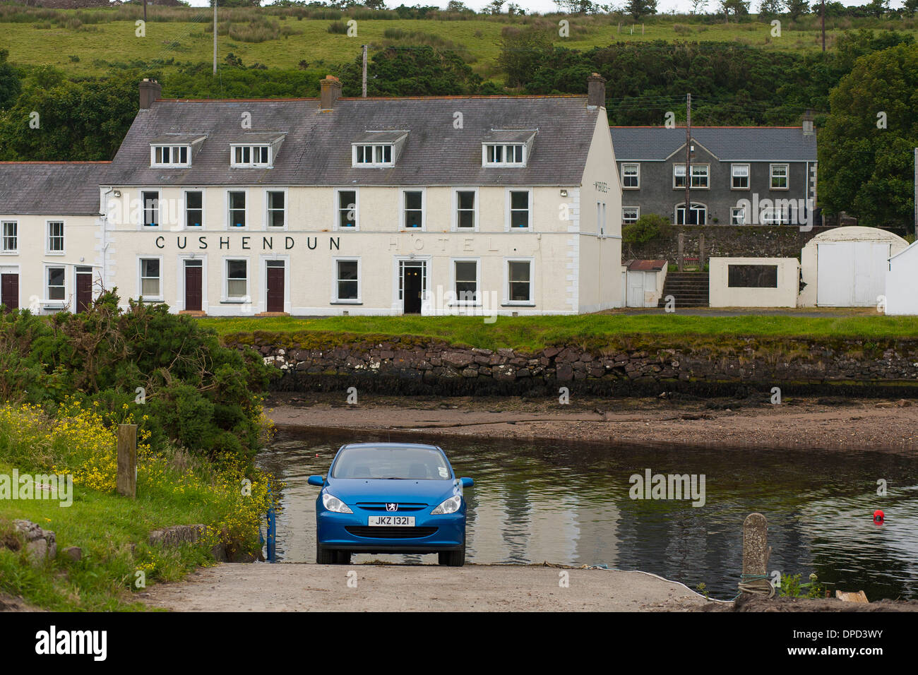 A blue car launches a boat from the boat ramp opposite the Cushendun Hotel on the River Dun in County Antrim Stock Photo