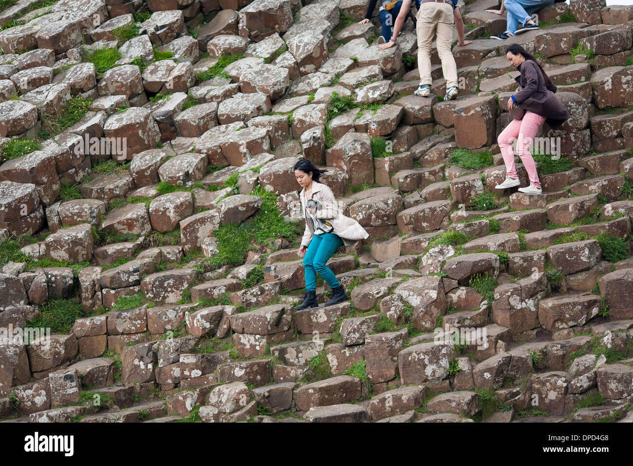 Visitors clamber and climb over the basalt columns that make up the world famous Giants Causeway in County Antrim. Stock Photo