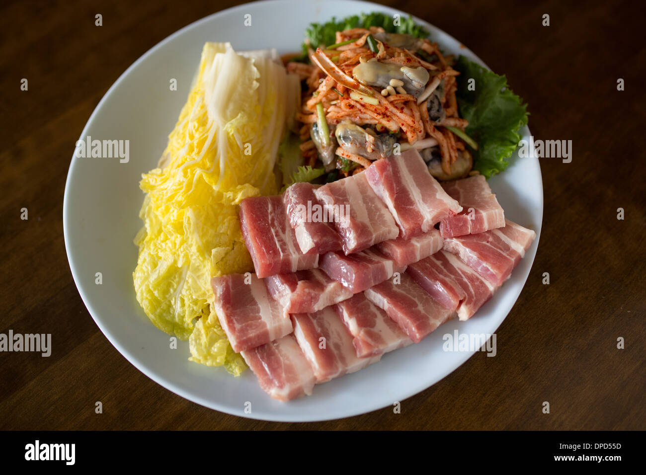 Korean BBQ plate with uncooked pork belly, oysters, and cabbage Stock Photo