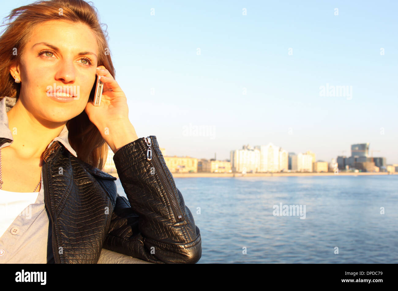 woman face 'by phone' 's[peaking by phone' portrait sunlight evening city water river urban Stock Photo