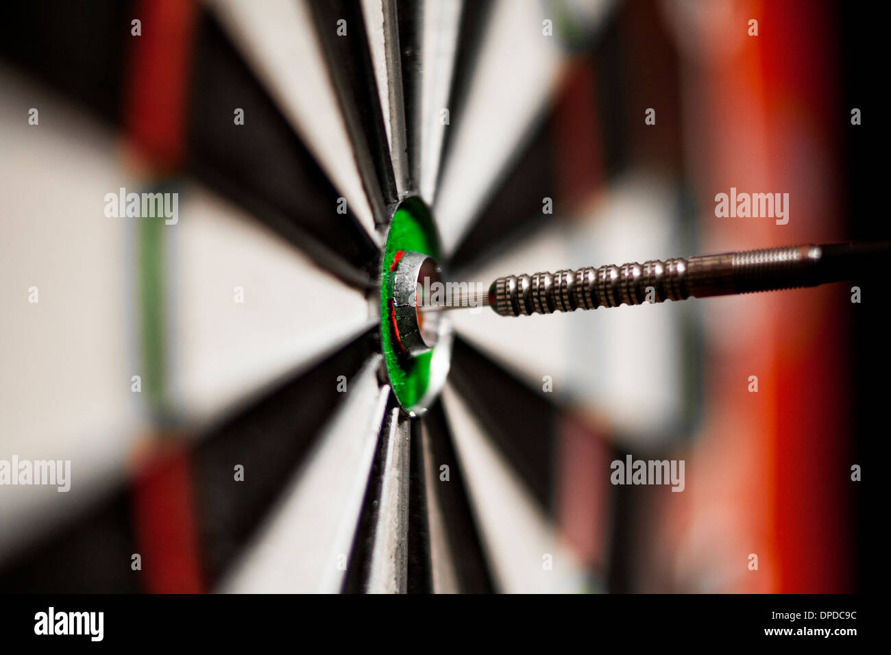 A dart in the bull's eye of a dart board Stock Photo