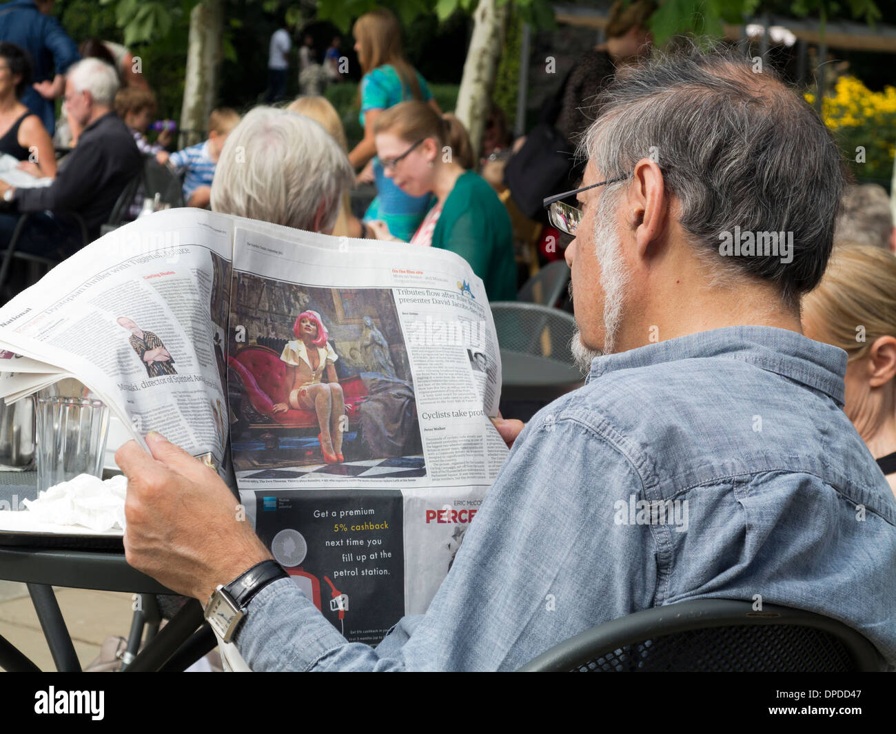 Man wearing glasses sitting and reading newspaper Pembroke Lodge café