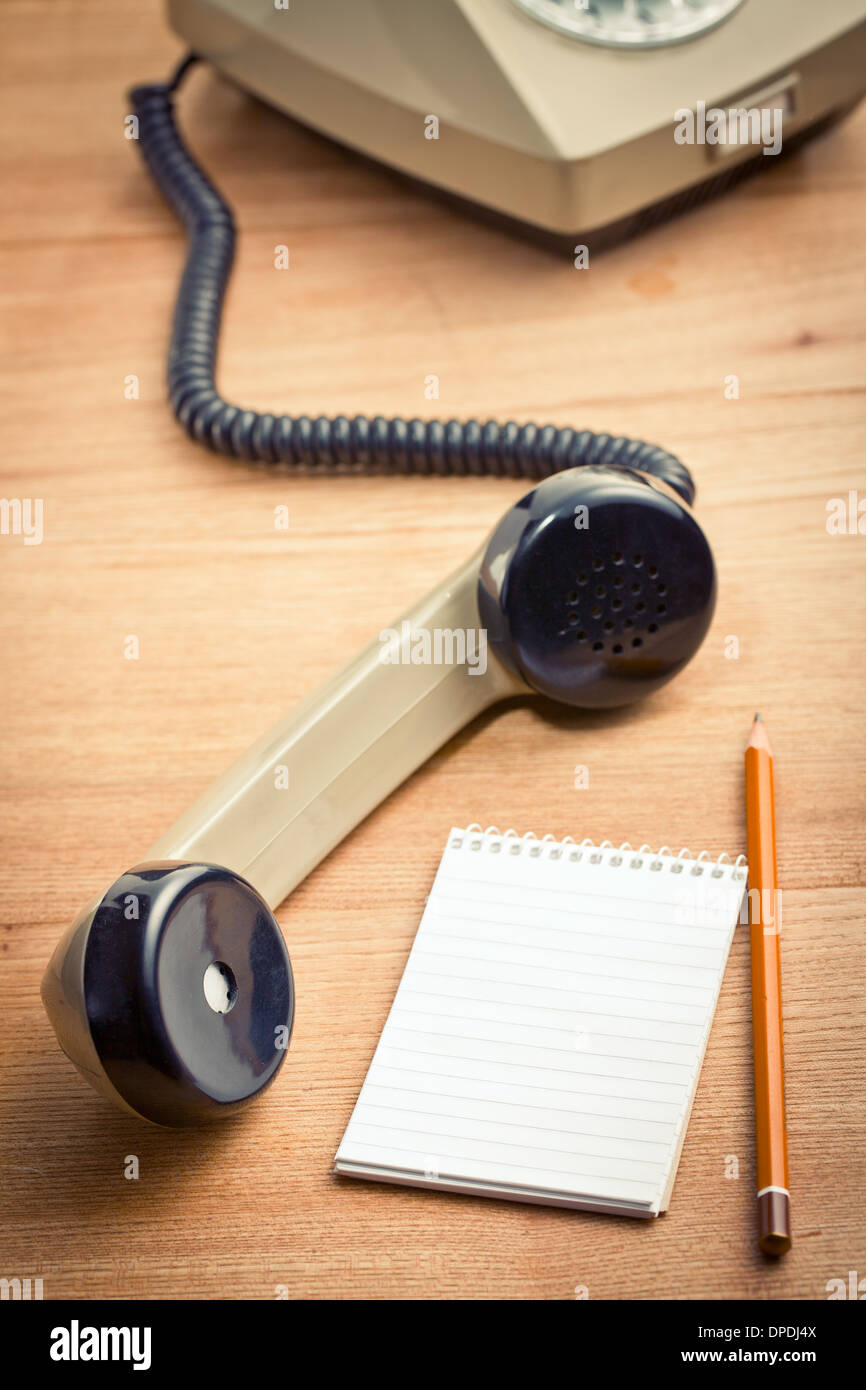 old telepnone handset with notebook on wooden table Stock Photo
