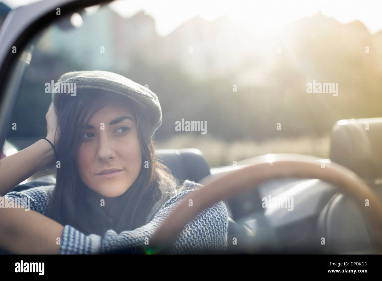Young woman wearing flat cap in convertible Stock Photo