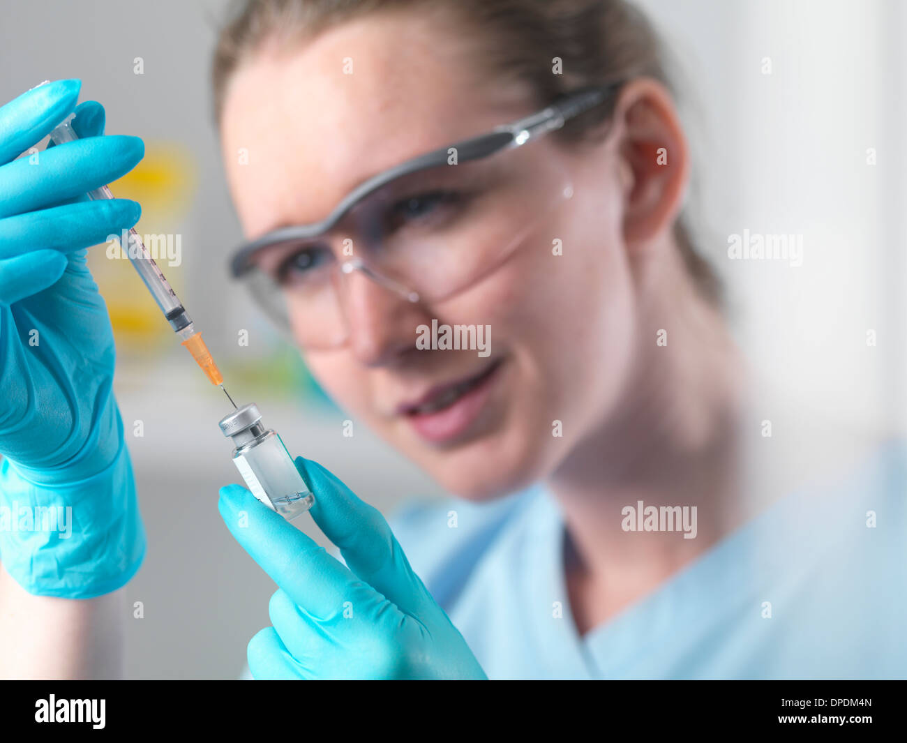 Healthworker holding up a syringe and vial, filling syringe in