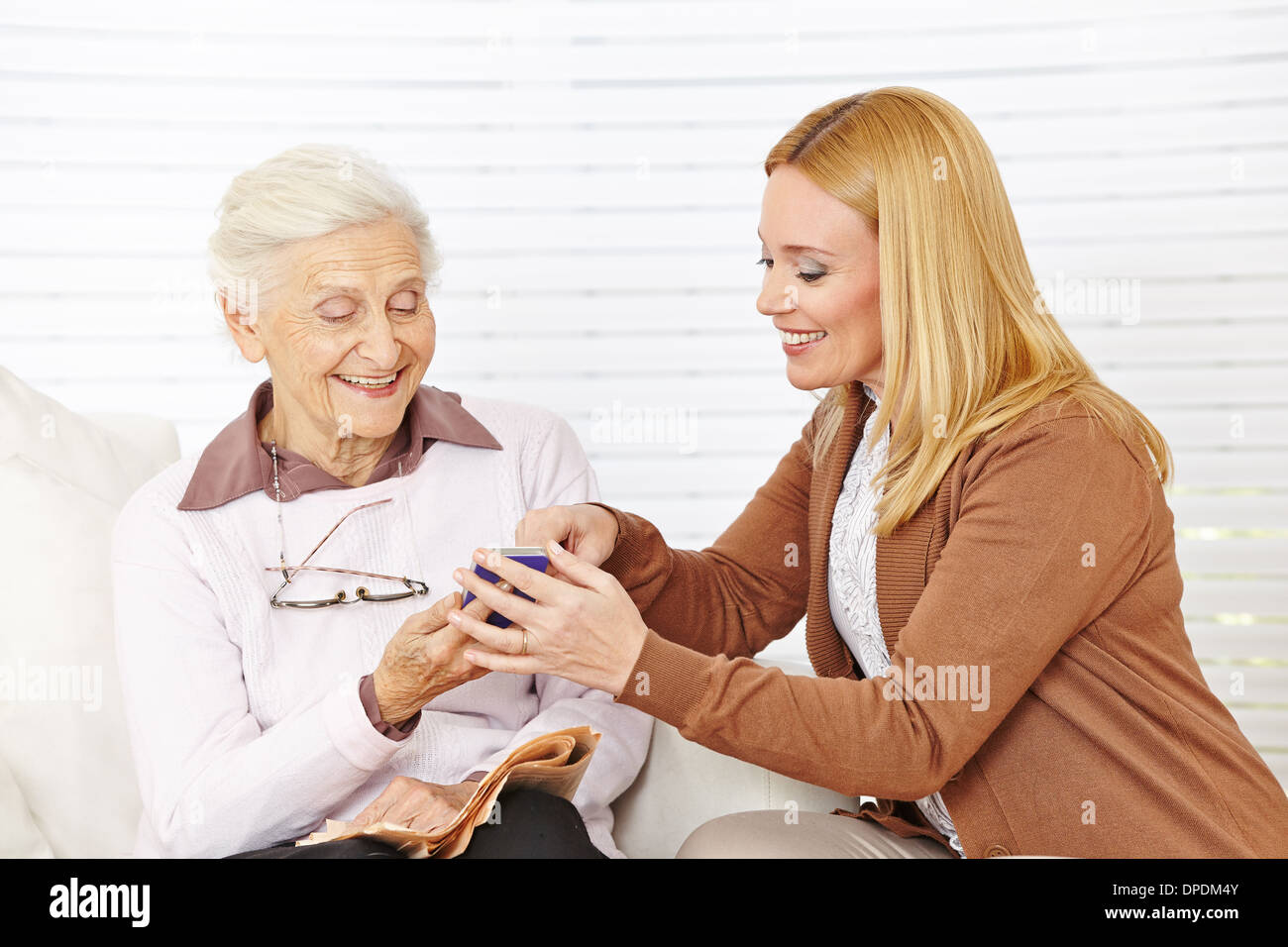 Download this stock image: Smiling woman helping senior woman to use her sm