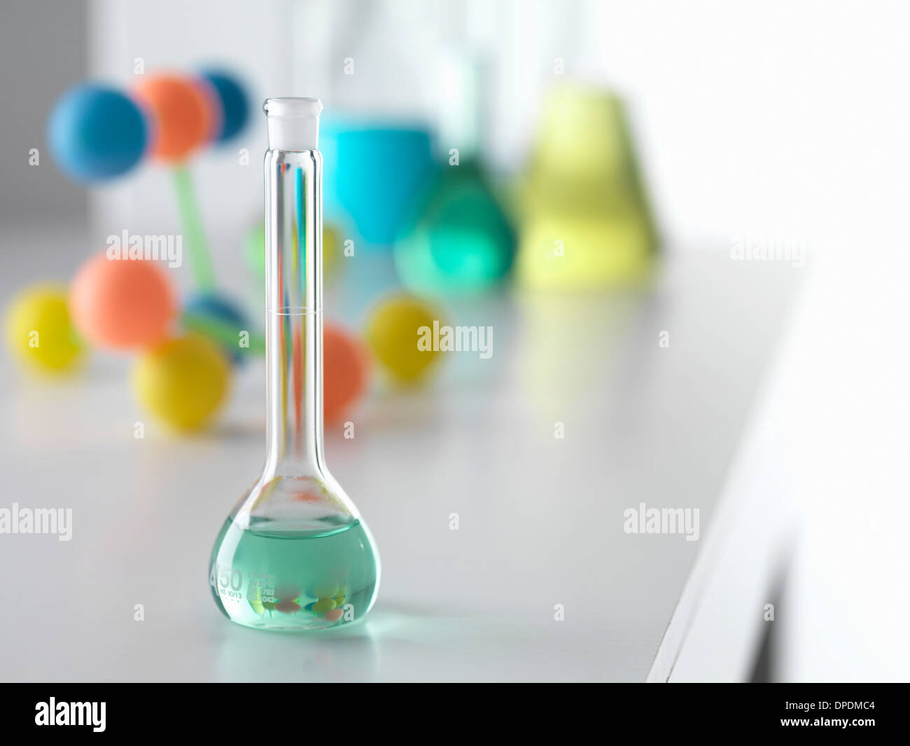 Beaker containing solution from chemical experiment with molecular model in background on lab
