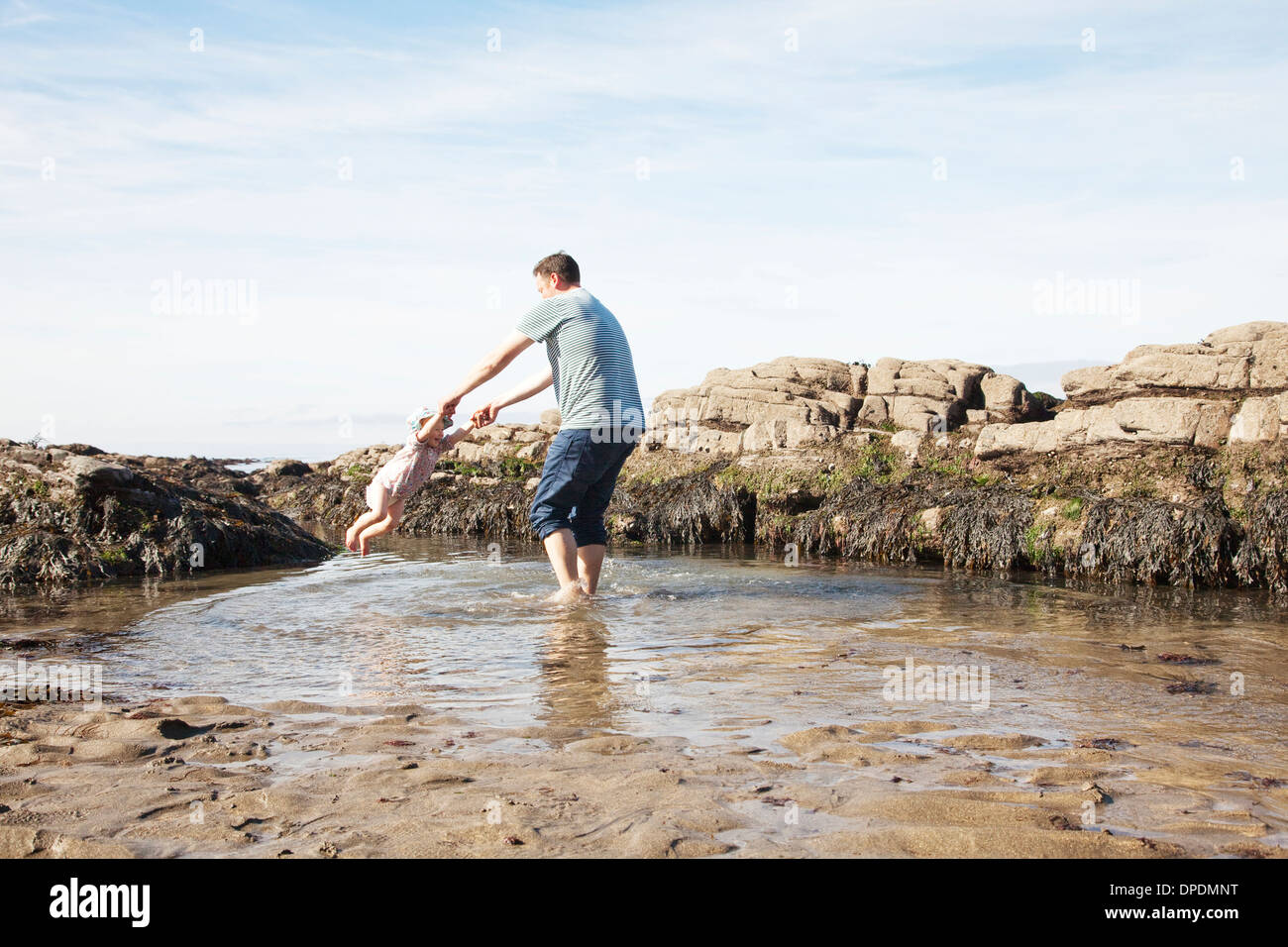 Father swinging child in pool Stock Photo