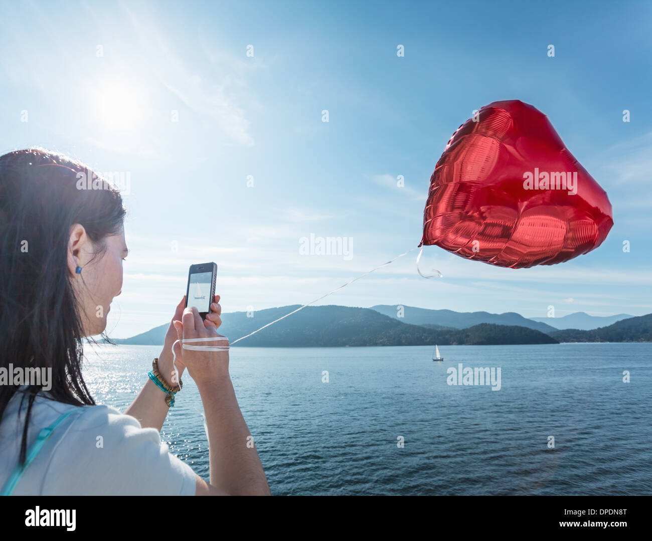 Mature woman photographing heart shaped balloon Stock Photo