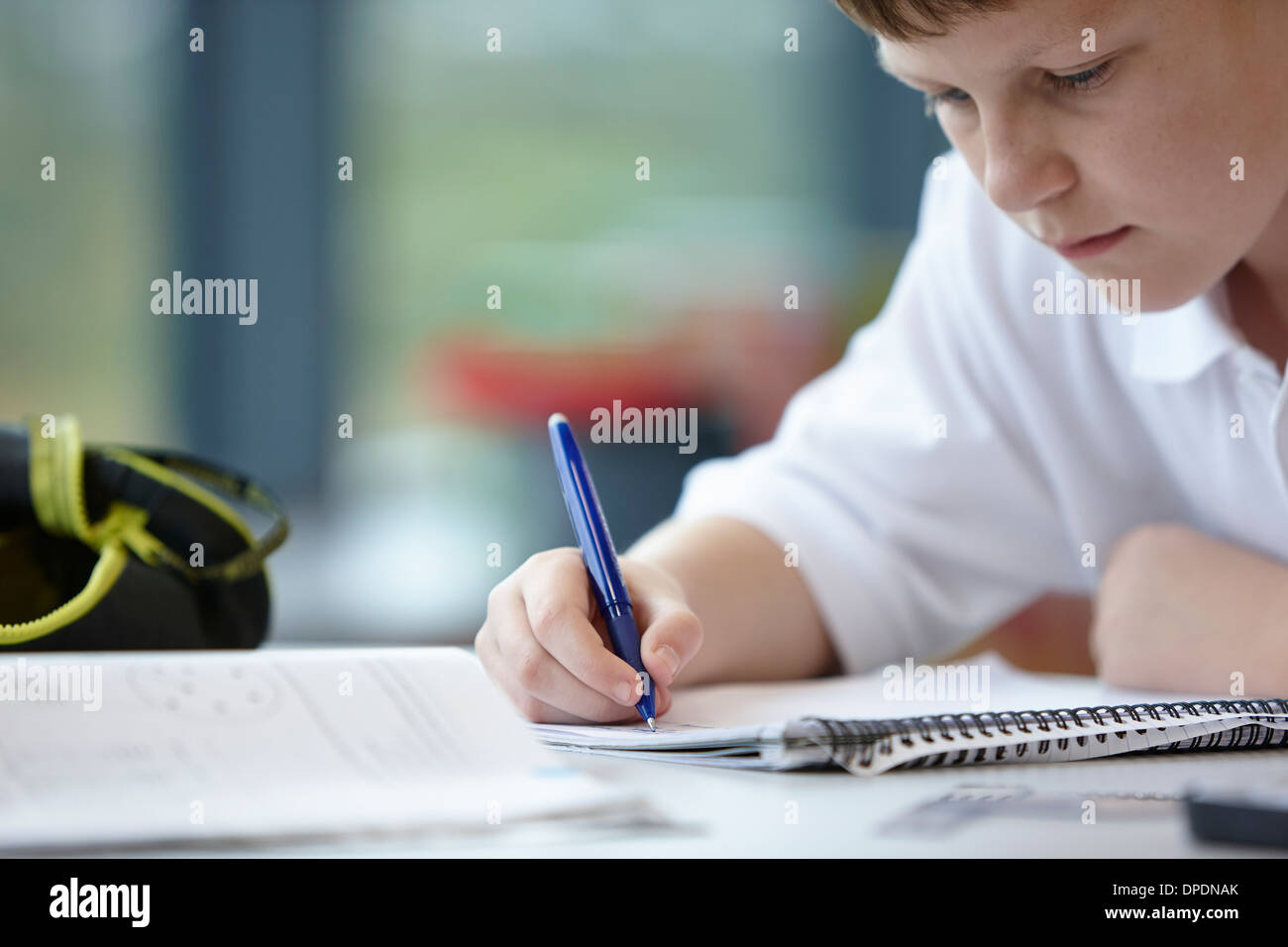 Close up of schoolboy writing in class Stock Photo