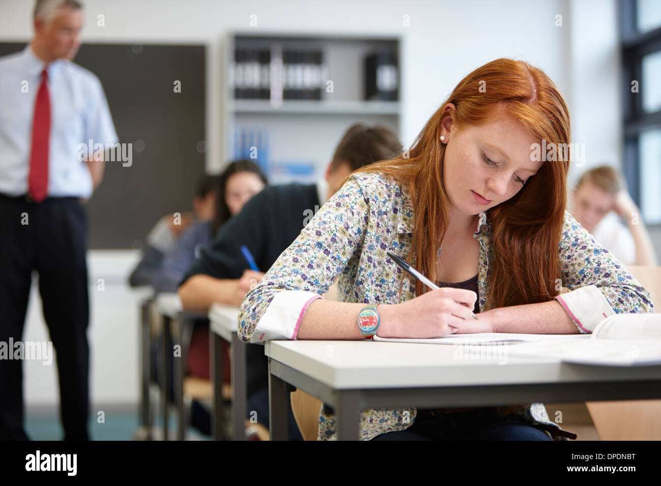 Teacher watching over teenagers in classroom Stock Photo