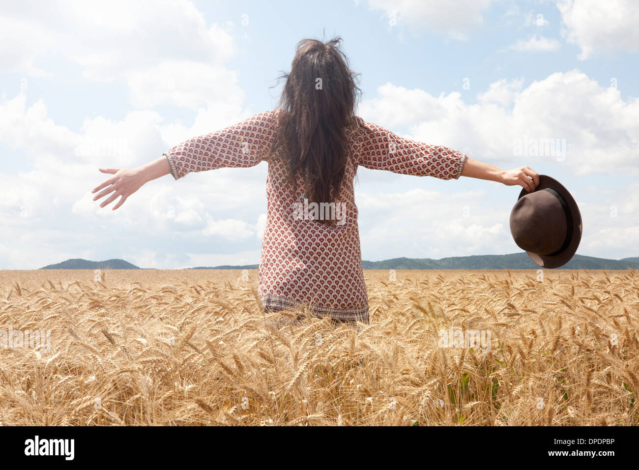 Mid adult woman standing in wheat field with arms out wide Stock Photo