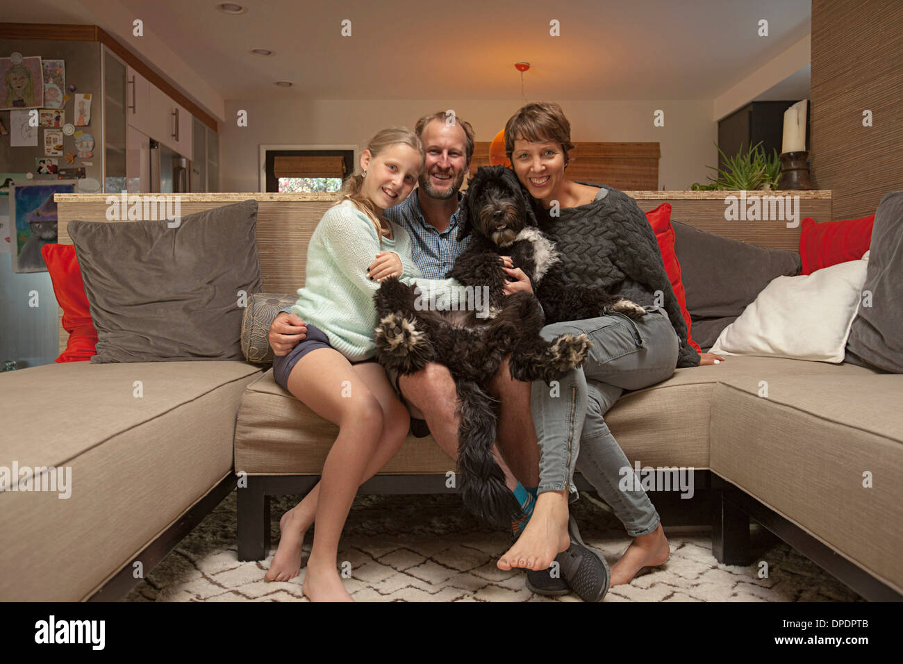 Portrait of parents, daughter and pet dog on sofa Stock Photo