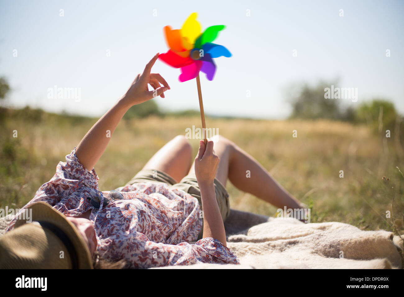 Woman lying in on back holding windmill Stock Photo