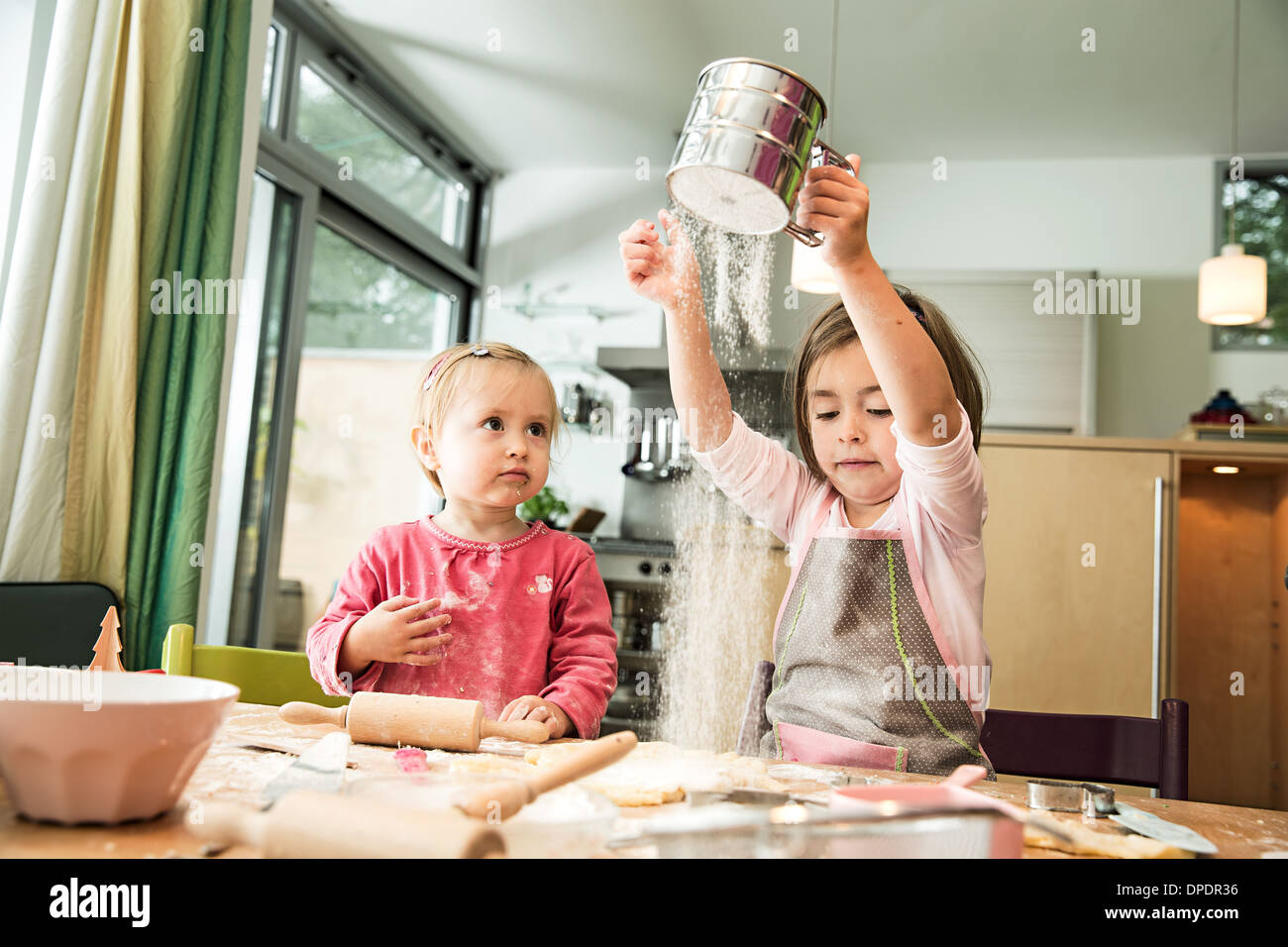 Girl sieving flour in kitchen Stock Photo