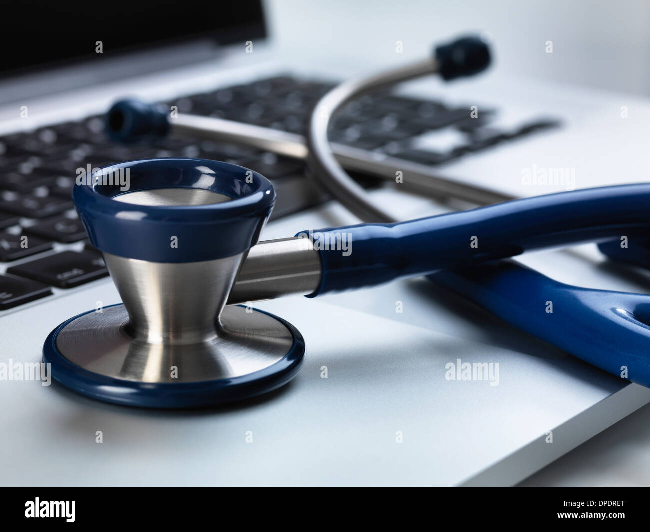 Stethoscope sitting on laptop illustrating online healthcare and doctor's desk Stock Photo