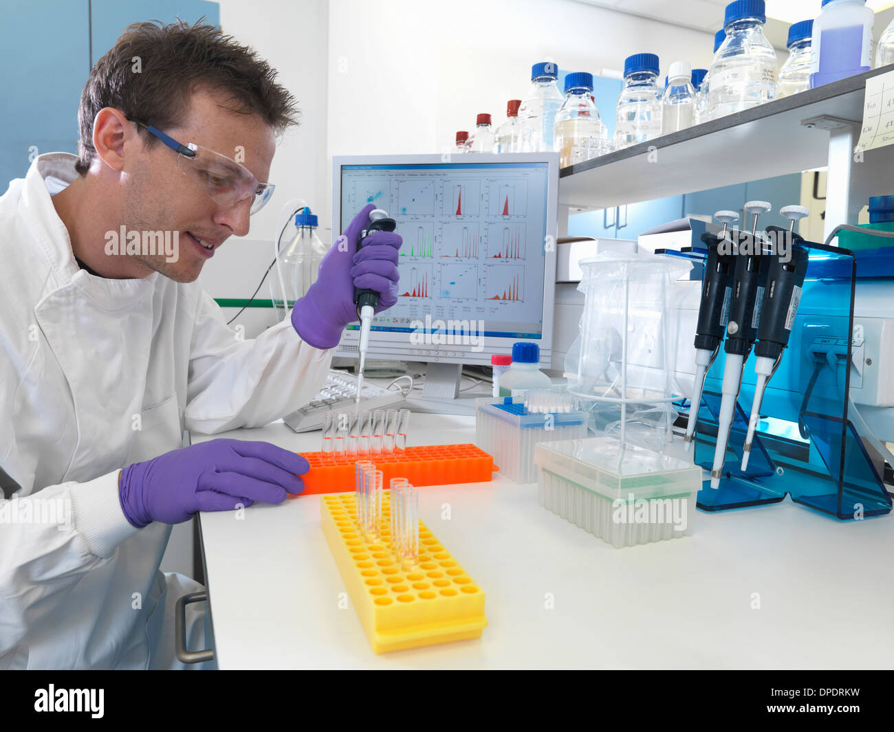 Male scientist pipetting sample into test tubes for analysis of cell ...