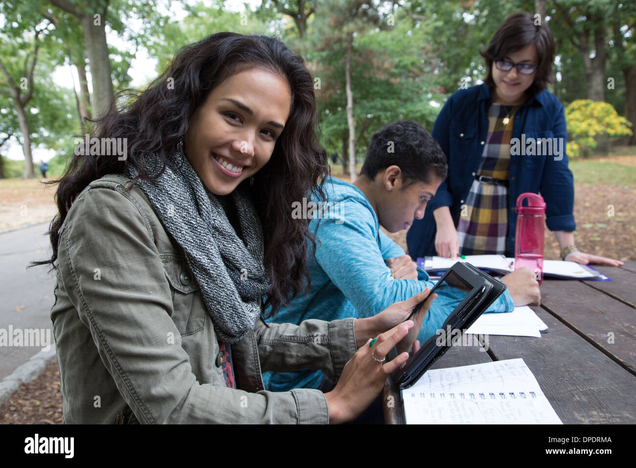 Students sitting at table in park doing homework Stock Photo