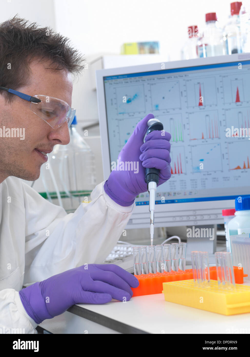 Male scientist pipetting sample into test tubes for analysis of cell ...