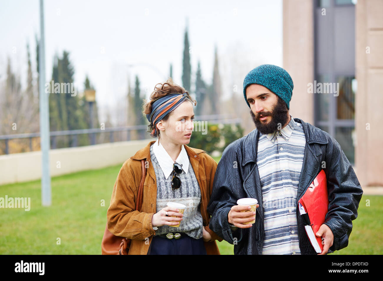 Hipster couple talking and drinking coffee to go at university campus Stock Photo