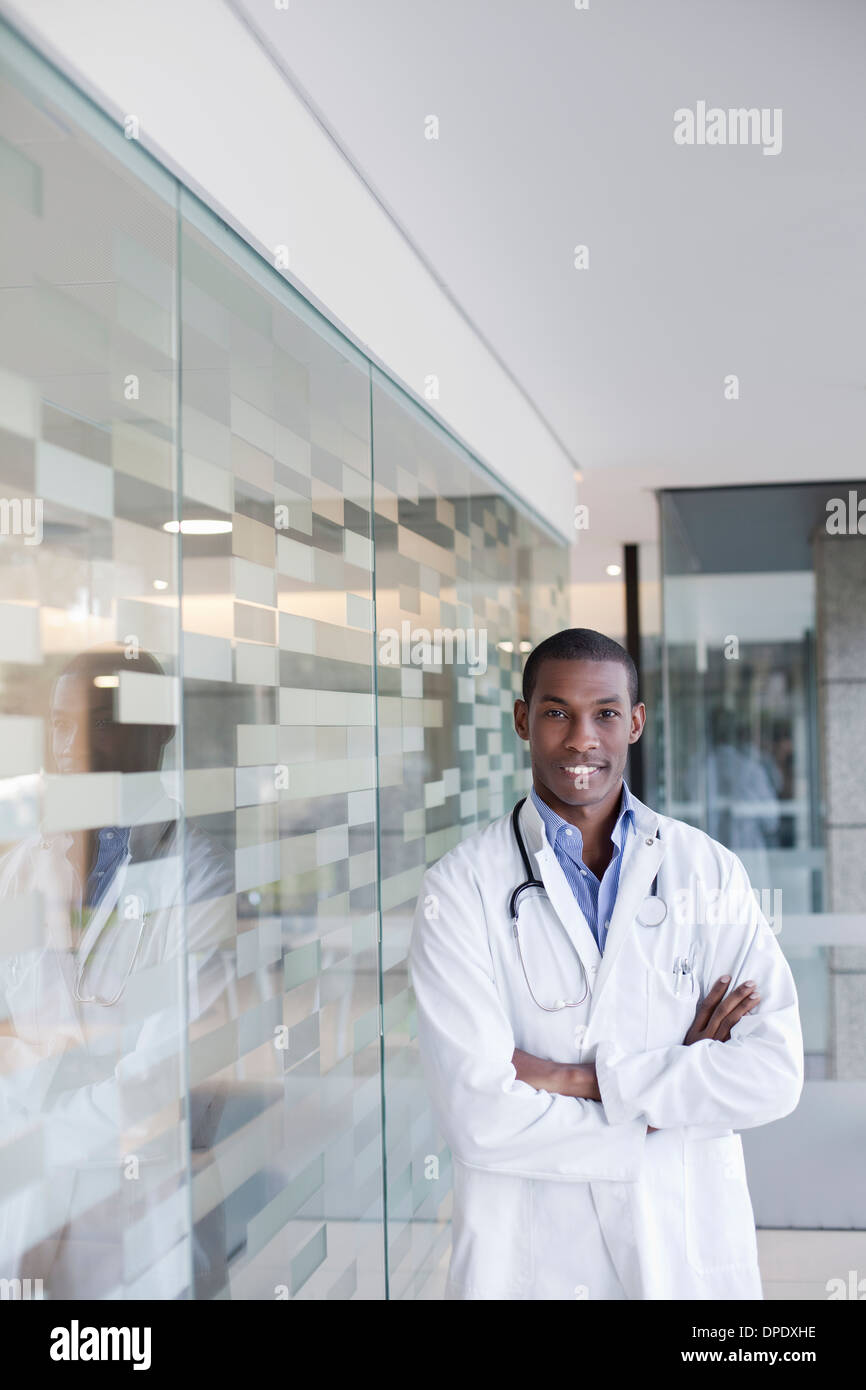 Doctor standing in hospital corridor with arms folded Stock Photo