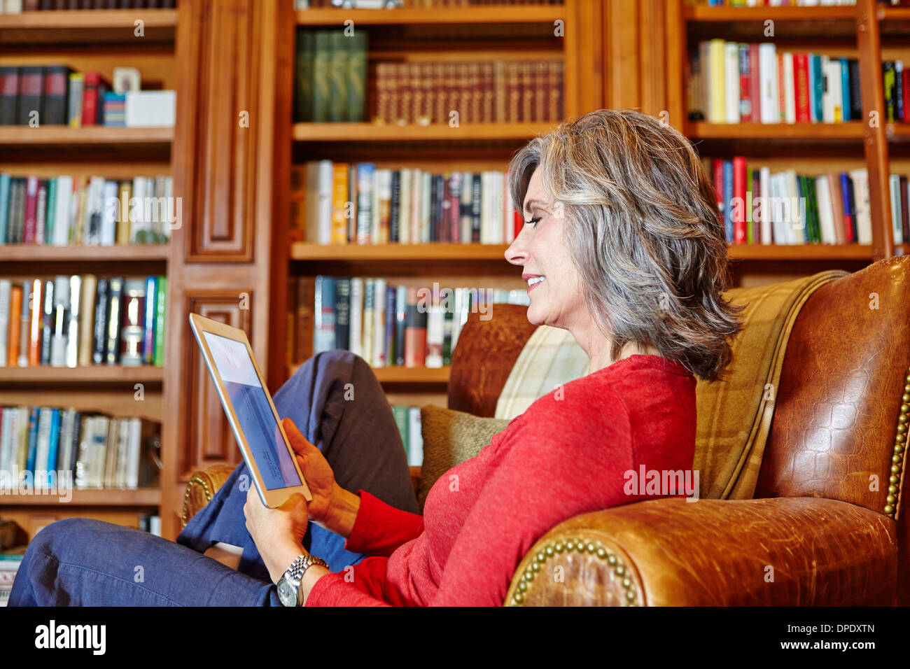 Mature woman sitting in home study using digital tablet Stock Photo