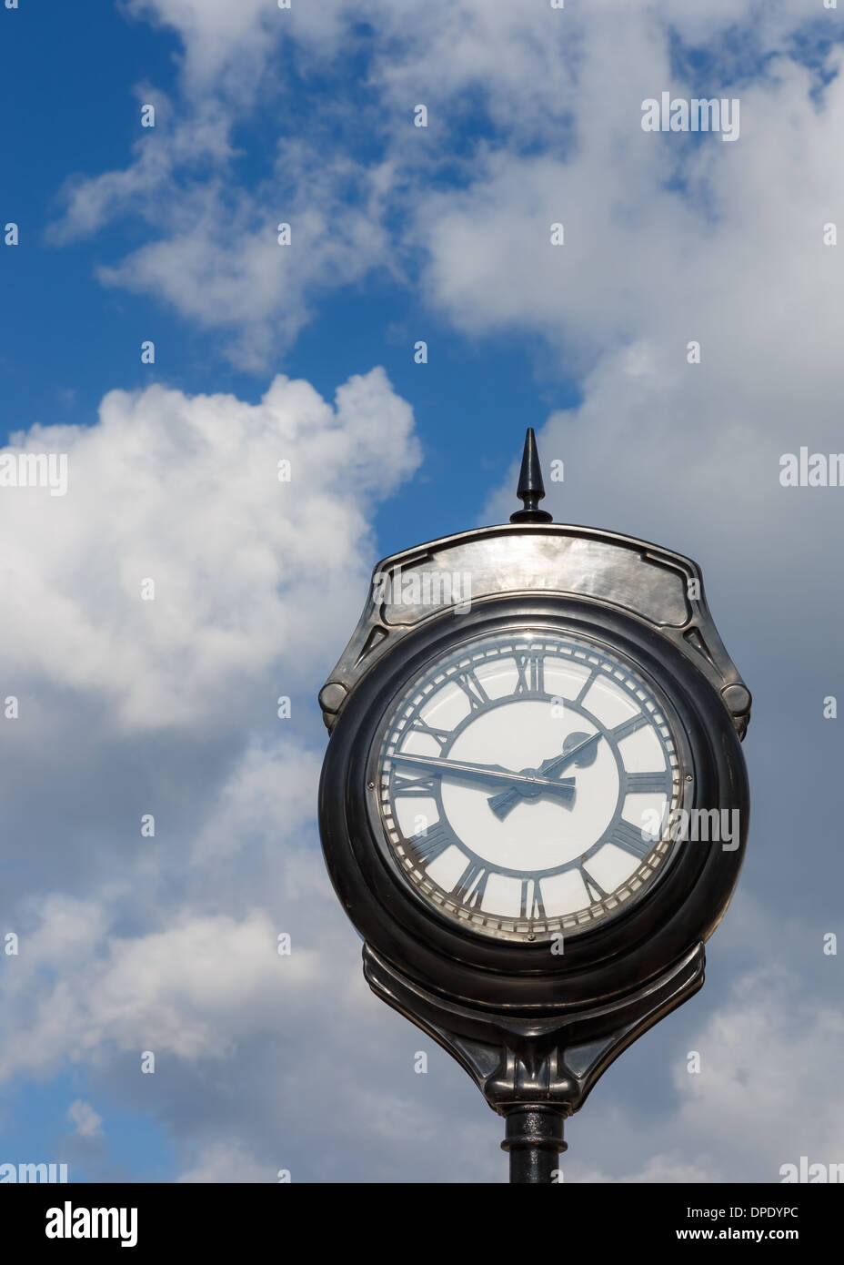 Old vintage exterior clock against blue sky and clouds in Greece Stock