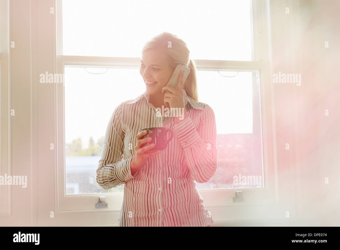 Young woman on phonecall, holding hot drink Stock Photo