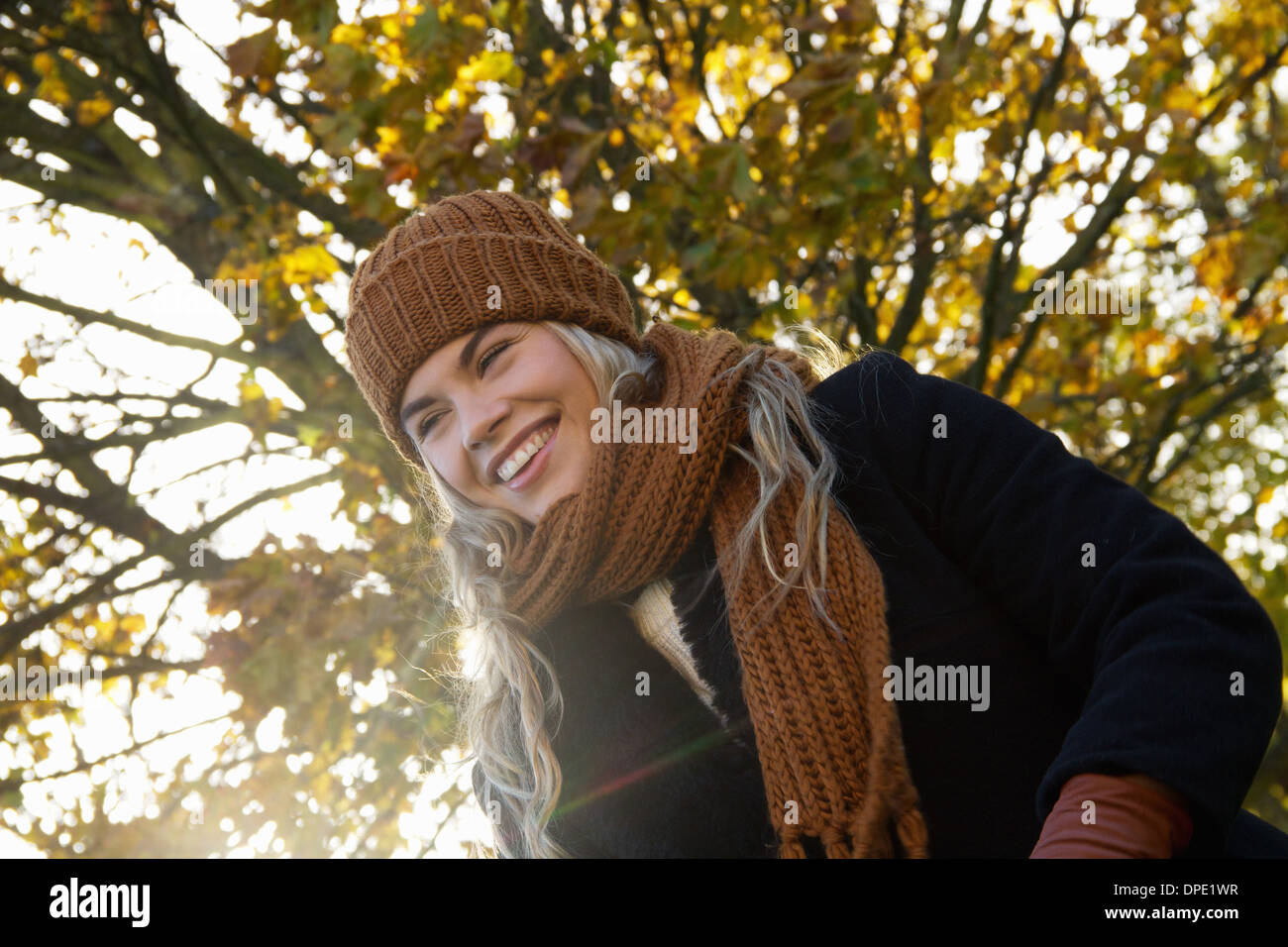Smiling young woman wrapped up in autumnal park Stock Photo