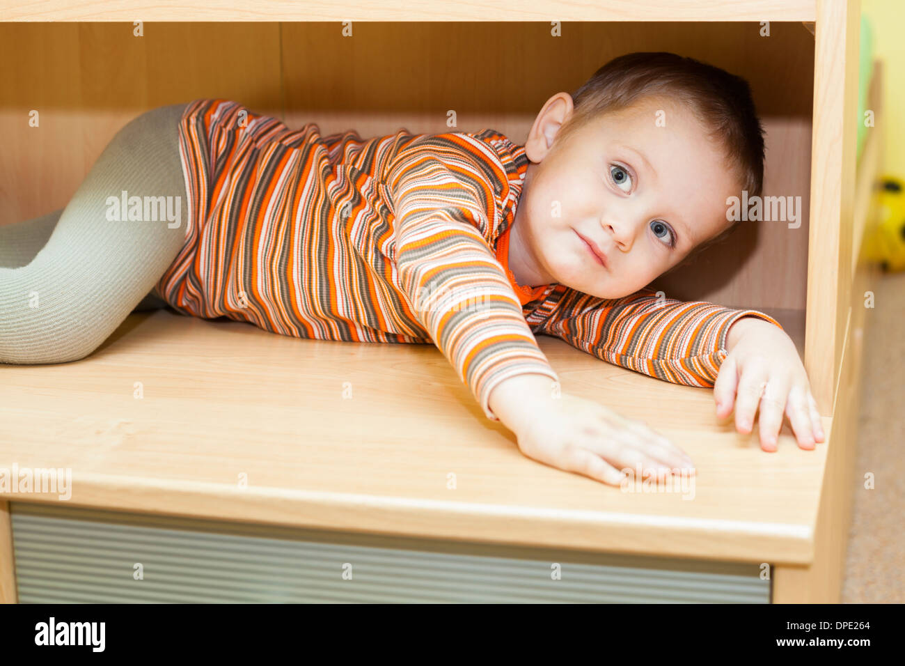 Cute child boy hiding in cupboard at home Stock Photo